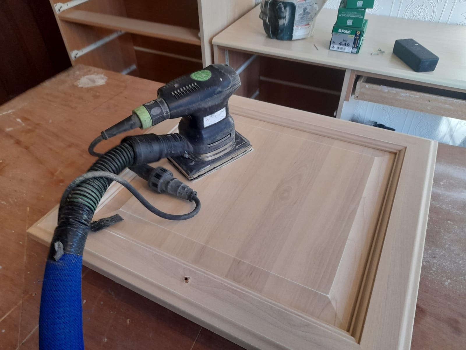Photo of a decorator’s professional 99% dust free sander being used to sand down a kitchen cabinet ready for the kitchen to be hand painted